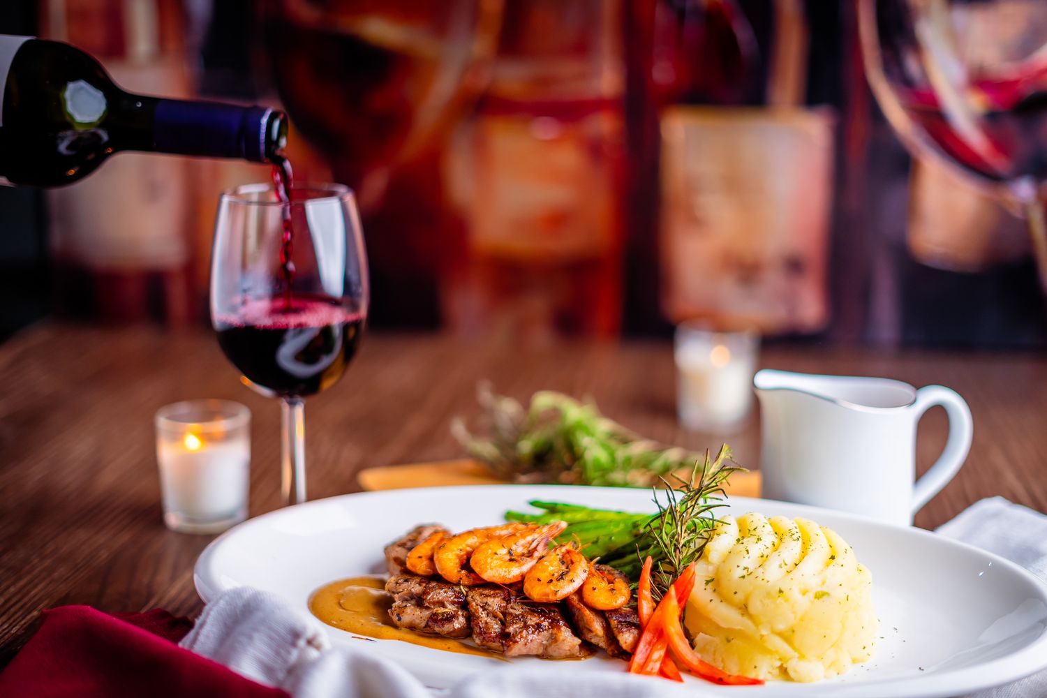 Red wine poured beside seared steak with shrimp